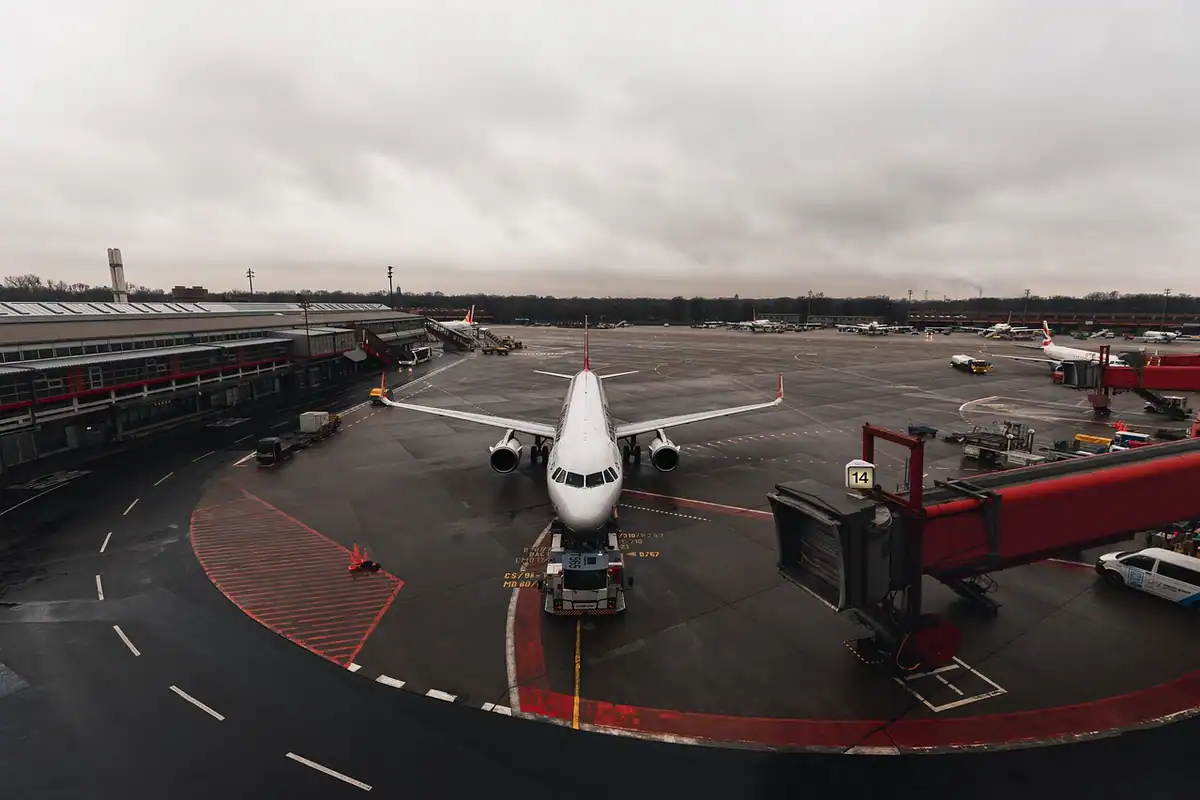 Avion pe platforma unui aeroport, lângă pasarela de îmbarcare, sub un cer înnorat