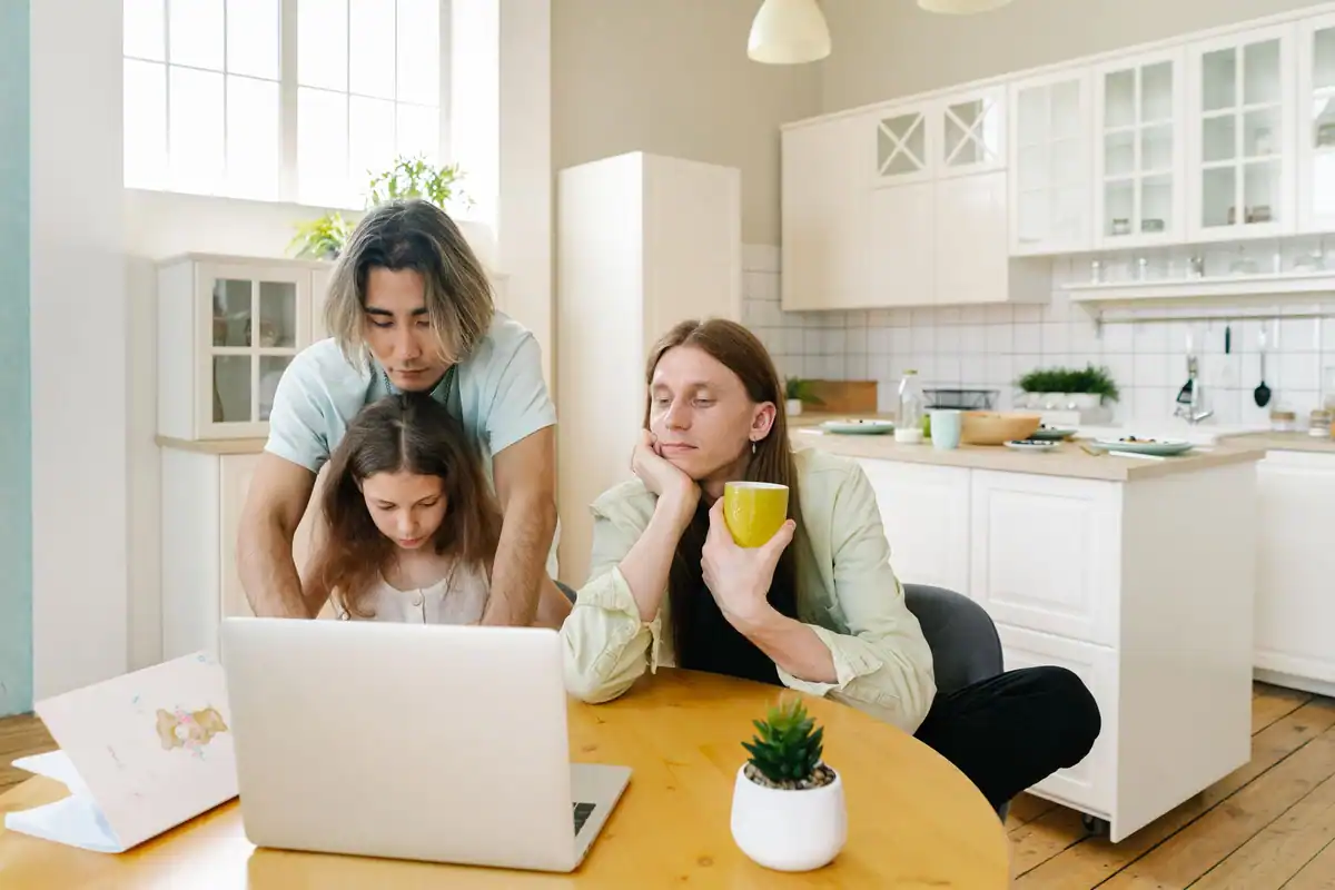 Familie adunată la masa din bucătărie, care își planifică programul uitându-se la laptop