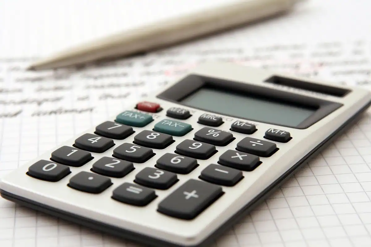 Calculator de birou și pix așezate pe o foaie cu cifre, pentru calculul bugetului