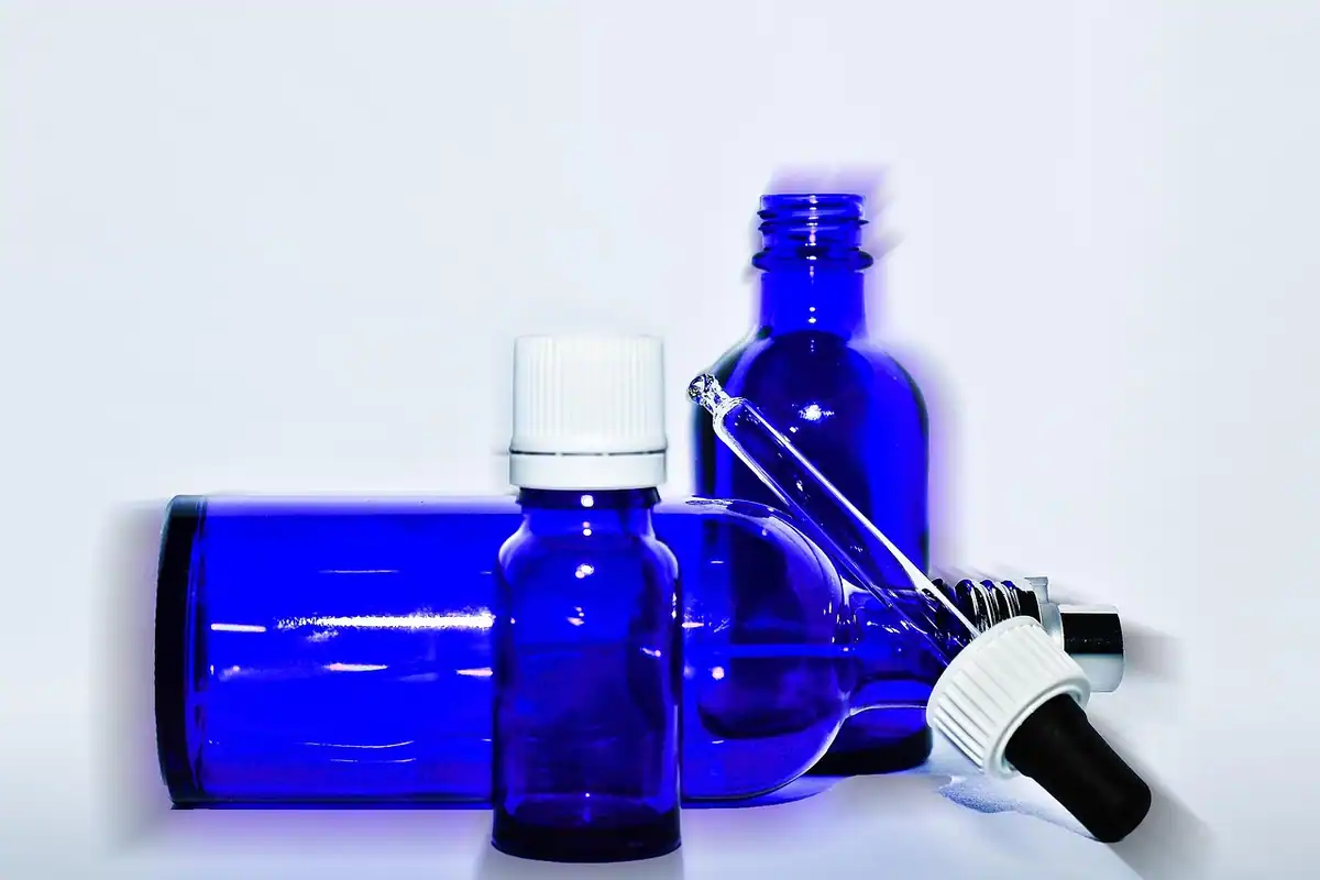 Sticluțe albastre cu pipetă pe un fundal alb, folosite pentru seruri și uleiuri cosmetice