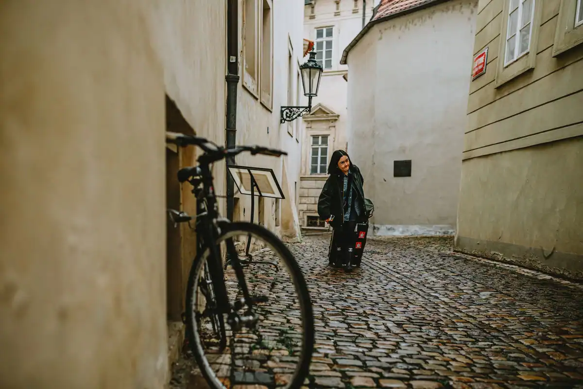 Femeie cu o bicicletă pe o alee pietruită dintr-un oraș vechi european